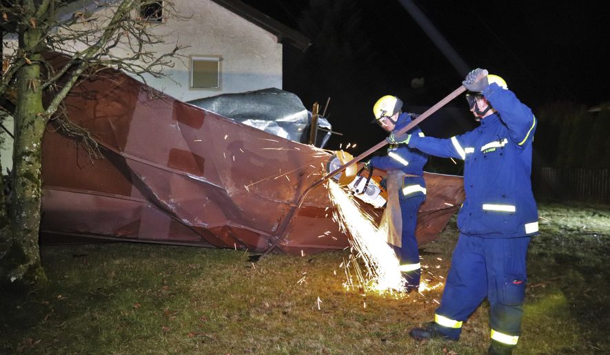 Members of the Sonthofen fire brigade and the sonthofen technical relief organisation are working on a roof that was blown off a house by heavy wind in Sonthofen, Germany, Feb. 11, 2020. The tin roof of the industrial plant had been blown onto an apartment building by strong gusts of wind. (Benjamin Liss/dpa via AP)