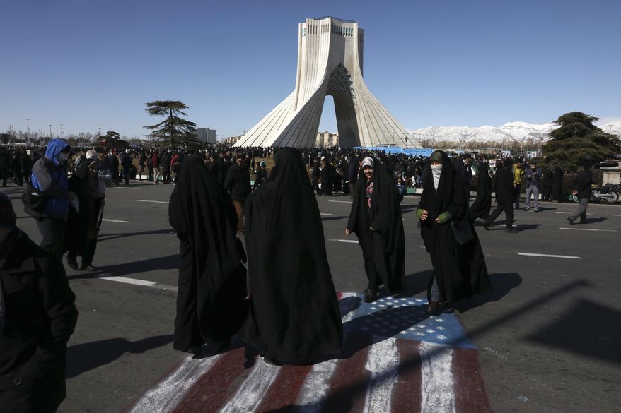Demonstrators walk on a painting of the U.S. flag in front of the Azadi (Freedom) tower during an annual rally celebrating 41st anniversary of Islamic Revolution, in Tehran, Iran, Tuesday, Feb. 11, 2020. Iranians were taking to the streets of Tehran and other cities and towns across the country on Tuesday for rallies and nationwide celebrations marking the anniversary of the 1979 Islamic Revolution when followers of Ayatollah Khomeini ousted U.S.-backed Shah Mohammad Reza Pahlavi. (AP Photo/Vahid Salemi)