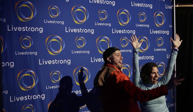 In this Monday, Feb. 3, 2020 photo, guest pose with a new logo for Livestrong at an event in Austin, Texas. The Livestrong cancer charity is on a mission to reinvent itself. It has survived a dramatic fall in contributions and donations since founder Lance Armstrong&#x27;s performance-enhancing drug scandal. (AP Photo/Eric Gay)