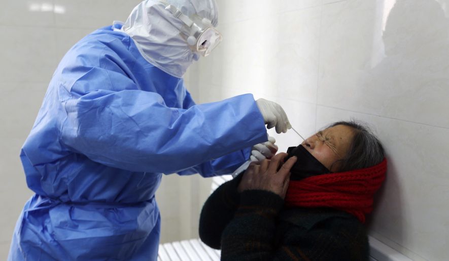 A doctor takes a swab from a woman to test for the COVID-19 virus at a fever clinic in Yinan county in eastern China's Shandong province on Wednesday, Feb. 12, 2020. China on Wednesday reported another drop in the number of new cases of a viral infection and 97 more deaths, pushing the total dead past 1,100 as postal services worldwide said delivery was being affected by the cancellation of many flights to China. (Chinatopix Via AP)