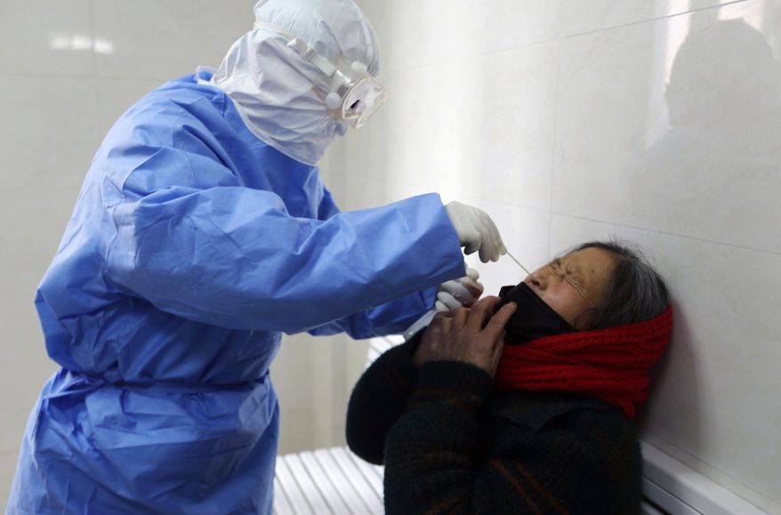 A doctor takes a swab from a woman to test for the COVID-19 virus at a fever clinic in Yinan county in eastern China's Shandong province on Wednesday, Feb. 12, 2020. China on Wednesday reported another drop in the number of new cases of a viral infection and 97 more deaths, pushing the total dead past 1,100 as postal services worldwide said delivery was being affected by the cancellation of many flights to China. (Chinatopix Via AP)