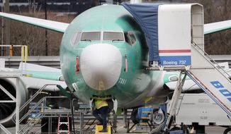 FILE - In this Dec. 16, 2019, file photo a worker looks up underneath a Boeing 737 MAX jet in Renton, Wash. Boeing sold no new airline jets in January, and now the company is worried that the virus outbreak in China could hurt airplane deliveries in the first quarter. (AP Photo/Elaine Thompson, File)