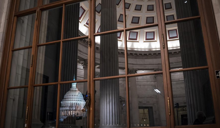 The Capitol is seen amid reflections of the Russell Senate Office Building in Washington. On Wednesday, Feb. 12, the Treasury Department releases federal budget data for January. (AP Photo/J. Scott Applewhite, File)