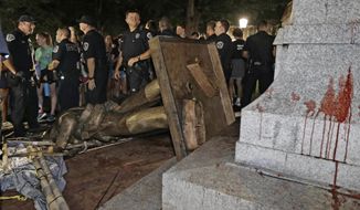 FILE - In this Aug. 20, 2018 file photo, police stand guard after the confederate statue known as Silent Sam was toppled by protesters on campus at the University of North Carolina in Chapel Hill, N.C.   Judge Allen Baddour ruled Wednesday, Feb. 12, 2020 that the Sons of Confederate Veterans didn’t have standing to bring the lawsuit that led to the hastily arranged deal that gave them possession of the statue known as Silent Sam, along with $2.5 million to maintain it. He  vacated the deal and also dismissed the underlying lawsuit brought by the SCV.  Critics had questioned how the deal was quietly struck with the UNC Board of Governors and approved just before Thanksgiving.    (AP Photo/Gerry Broome, File)