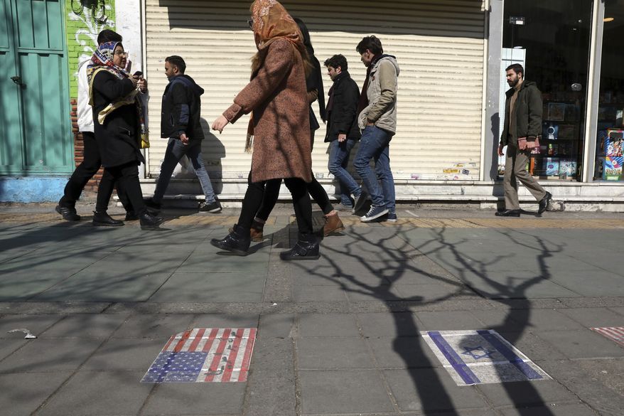 Pedestrians walk past representations of the U.S. and Israeli flags pasted on the ground on Enqelab-e-Eslami (Islamic Revolution) street in downtown Tehran, Iran, Thursday, Feb. 13, 2020. Thousands of Iranian candidates approved to run in parliamentary elections kicked off their campaigns Thursday ahead of next week's vote, even after authorities barred thousands of others from running, mainly reformists and moderates. (AP Photo/Vahid Salemi)