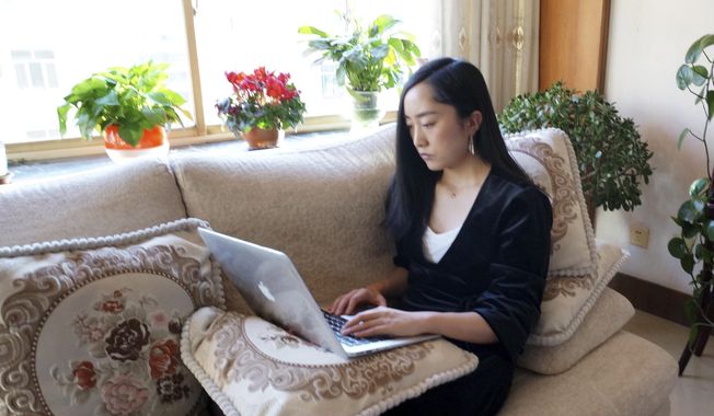 In this Wednesday, Feb. 12, 2020, photo released by Maggie Zhang, Zhang uses a laptop computer at her parents&#x27; home in in the northwestern city of Zhangye in Gansu province. Zhang, founder of SheTalks, a company in Beijing that organizes events for women, is working out of her parents&#x27; apartment after she went back for the Lunar New Year and said she might stay through March. (Maggie Zhang via AP)