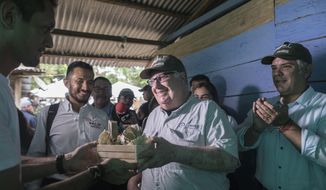 In this Jan. 29, 2020 photo, Howard Buffet receives presents during a visit, with Colombia&#39;s President Ivan Duque, right, to a cocoa farm in La Gabarra, Colombia. As a philanthropist, Buffet&#39;s priority now is helping Colombia and El Salvador, whose fight against drug trafficking has a direct impact on the U.S. (AP Photo/Ivan Valencia)