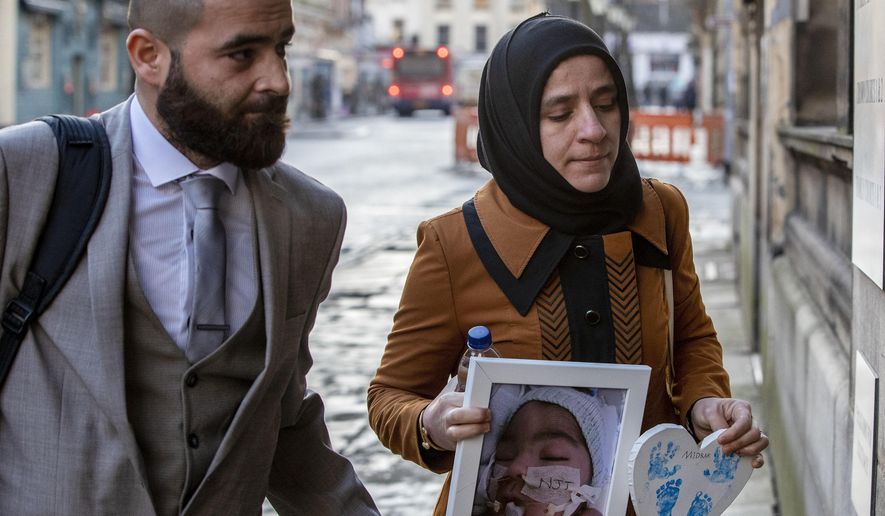 FILE - In this Jan. 20, 2020 file photo, Karwan Ali, left, and Shokhan Namiq, hold a picture of their son, in Preston, England. The parents of a baby who was declared brain dead by doctors has lost the latest round of a legal battle in Britain’s courts to keep him on life support. Britain’s Court of Appeal on Friday, Feb. 14 rejected an attempt by Karwan Ali and Shokhan Namiq to overturn a High Court order that doctors could stop treating their infant son Midrar Ali. (Peter Byrne/PA via AP)