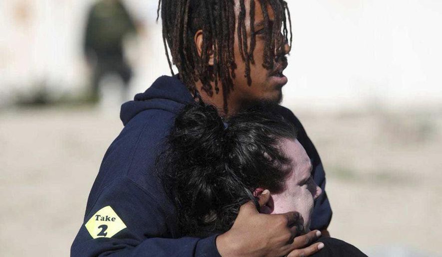 People who were in the building where a shooting took place console each other and watch the investigation at a Rancho Mirage medical office building, in Rancho Mirage, Calif. on Feb. 14, 2020. Two men were found dead in a Southern California medical office Friday after reports of a shooting, authorities said. The shooting in Rancho Mirage appeared to be "an isolated incident," the Riverside County Sheriff's Department said in a tweet. (Jay Calderon/The Desert Sun via AP )