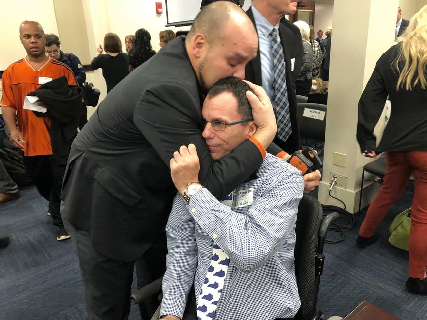 In this Wednesday, Feb. 12, 2020, photo, Eric Crawford, center right, is hugged by another medical marijuana advocate after a bill to legalize medical cannabis in Kentucky was approved by a state House committee, in Frankfort, Ky. Kentucky House Speaker David Osborne said Friday that the bill could possibly come up for a House vote as soon as next week. (AP Photo/Bruce Schreiner)