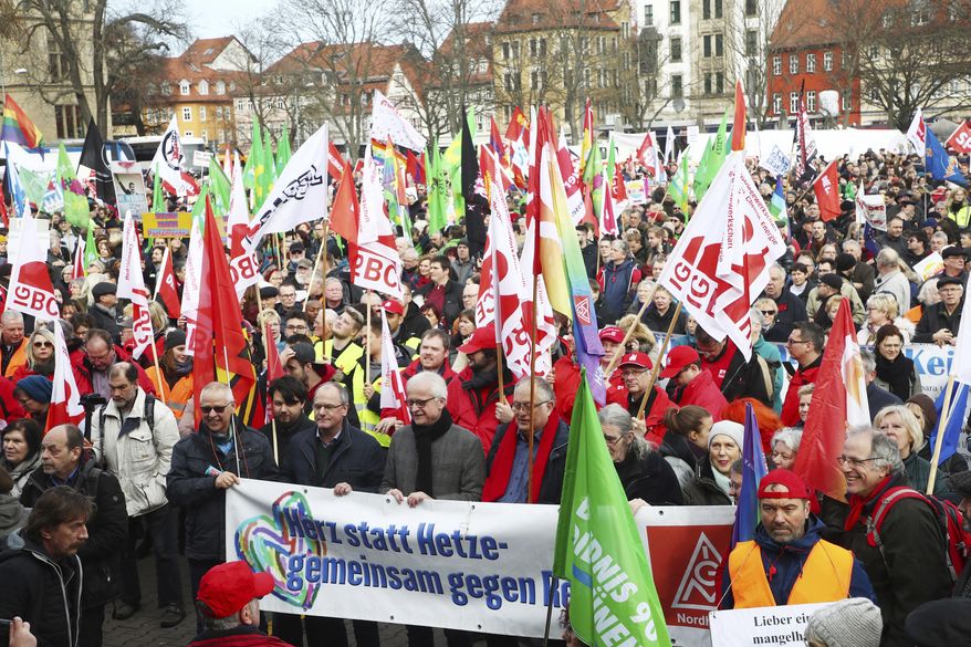 Demonstrators attend a rally against the ousting of a popular governor by a far-right and two centrist parties in Erfurt, Germany, Saturday, Feb. 15, 2020. The politician Thomas Kemmerich was elected as Thuringian Prime Minister with votes of the far-right Alternative fuer Deutschland (AfD) party. The poster reads: Heart instead of agitation - together against the right. (Bodo Schackow/dpa via AP)
