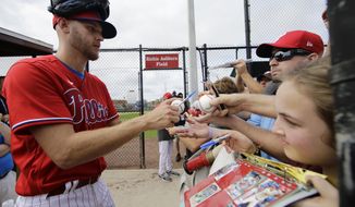 Philadelphia Phillies Zack Wheeler, left, signs autographs during a spring training baseball workout Friday, Feb. 14, 2020, in Clearwater, Fla. (AP Photo/Frank Franklin II)
