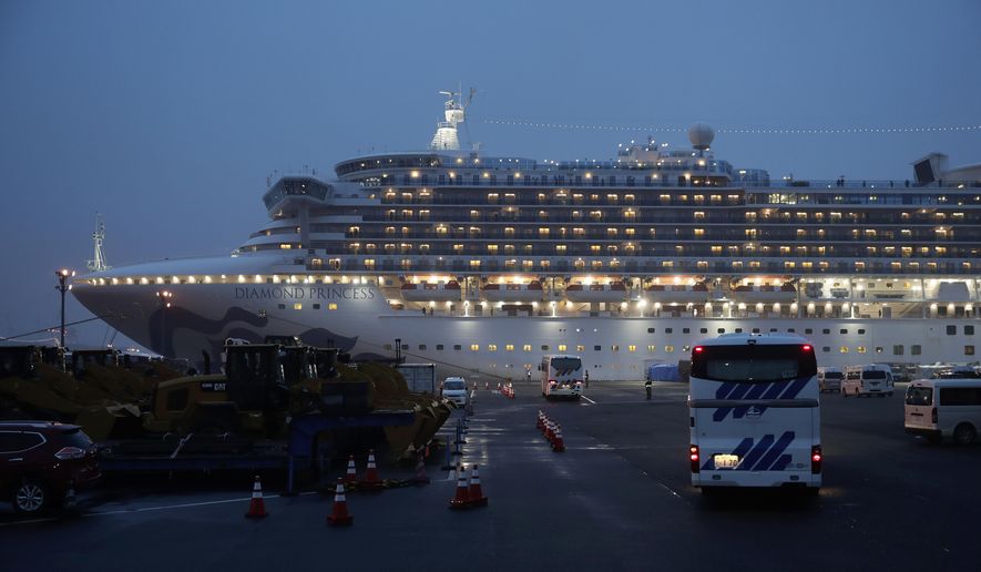 Buses arrive at a port as the Japan Self-Defense Forces prepare to move American passengers from the quarantined Diamond Princess cruise ship Sunday, Feb. 16, 2020, at Yokohama Port, near Tokyo. The U.S. says Americans aboard a quarantined ship will be flown back home on a chartered flight Sunday, but that they will face another two-week quarantine. (AP Photo/Jae C. Hong)