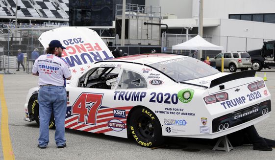 Crew members make adjustments to Joe Nemecheck&#39;s car sponsored by Patriots PAC of America during practice for the NASCAR Xfinity Series auto race at Daytona International Speedway, Friday, Feb. 14, 2020, in Daytona Beach, Fla. Trump is scheduled to be present for the Daytona 500 on Sunday and he will find this environment as welcoming as one of his campaign rallies. (AP Photo/Terry Renna)