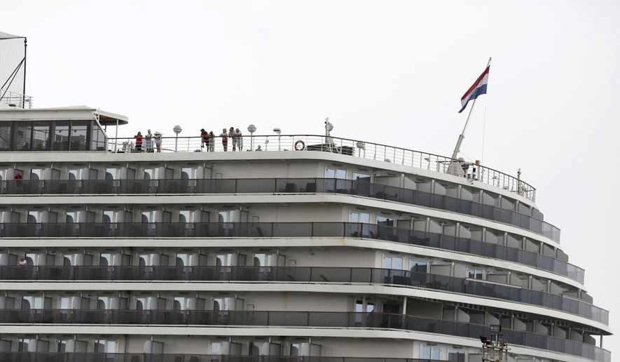 Passengers stand on the top deck of the MS Westerdam while the cruise ship is docked in Sihanoukville, Cambodia Monday, Feb. 17, 2020. The feel-good story of how Cambodia allowed a cruise ship to dock after it was turned away elsewhere in Asia for fear of spreading the deadly virus that began in China has taken a dark turn after a passenger released from the ship tested positive for the virus. (AP Photo)