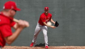 St. Louis Cardinals pitcher Jack Flaherty, right, works on fielding a ball hit back to him by bullpen coach Bryan Eversgerd during spring training baseball practice Sunday, Feb. 16, 2020, in Jupiter, Fla. (AP Photo/Jeff Roberson)