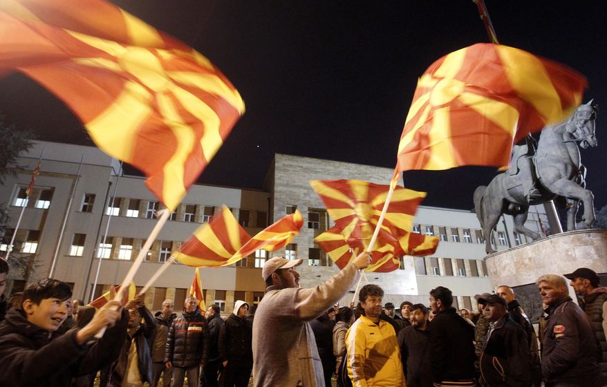 People waving national flags gather for a rally, titled "Walking for Justice," organized by the ruling Social Democrats, starting outside the parliament building and ending in front of the complex of national courts, in Skopje, North Macedonia, Monday, Feb. 17, 2020. Some thousands of supporters of the ruling Social Democrats marched peacefully in the capital Skopje late on Monday in support of a new law on public prosecution and demanded national courts be more vigorous in deciding cases related to corruption allegations of the former conservative government members.(AP Photo/Boris Grdanoski)