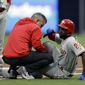 FILE - In this June 3, 2019, file photo, Philadelphia Phillies&#39; Andrew McCutchen, right, is helped by a trainer after injuring his knee while trying to get back to first base during the first inning of a baseball game against the San Diego Padres in San Diego. McCutchen says he plans to be ready for opening day after the injury cut short his 2019 season. (AP Photo/Gregory Bull, File)