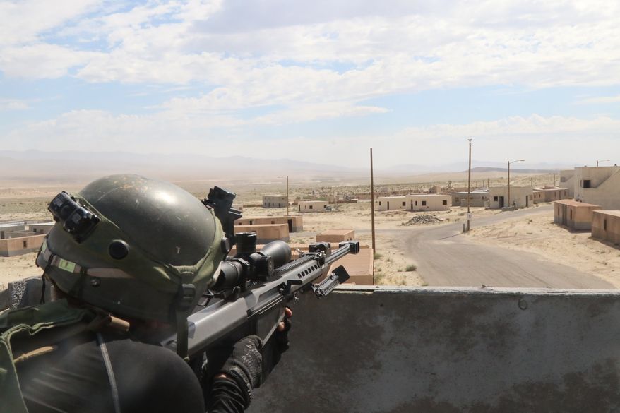 A U.S. Soldier with the 11th Armored Cavalry Regiment surveys the battlefield with a simulated Barrett M107 .50 caliber Sniper Rifle in the city of Razish, National Training Center, Fort Irwin, California, July 12, 2019. (U.S. Defense Department photo.)