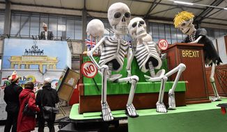 A satiric carnival float depicting the Brexit and British members of Parliament as skeletons, is watched by revellers during a preview in a hall in Cologne, Germany, Tuesday, Feb. 18, 2020. The traditional carnival parades on Rosemonday make fun of politics and are watched by hundreds of thousands in the streets of Cologne, Duesseldorf and Mainz. (AP Photo/Martin Meissner)