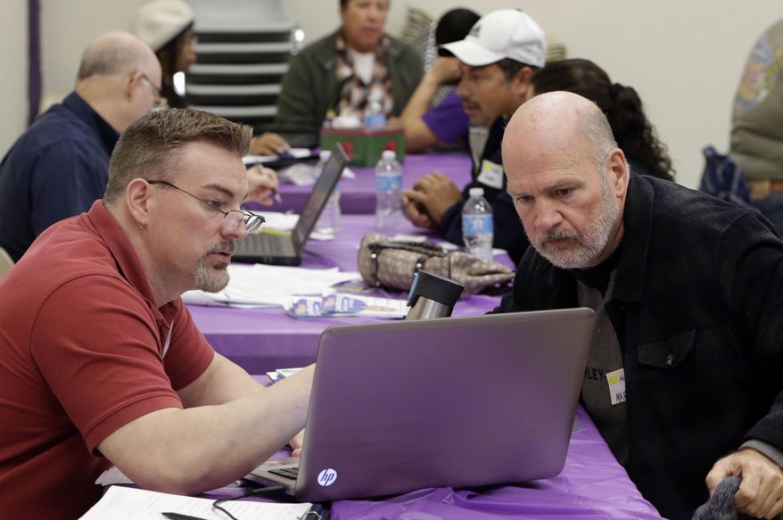 FILE - In this March 31, 2014 file photo Keith Saunders, left, a certified Cover California insurance agent, explains a health insurance plan to Mark Tammes at a registration site in Sacramento, Calif. More than 1.5 million people in California have purchased health insurance through the taxpayer funded marketplace, Covered California, state officials announced, Tuesday, Feb. 18, 2020. It is the first increase in enrollment after three years of decline. (AP Photo/Rich Pedroncelli, File)