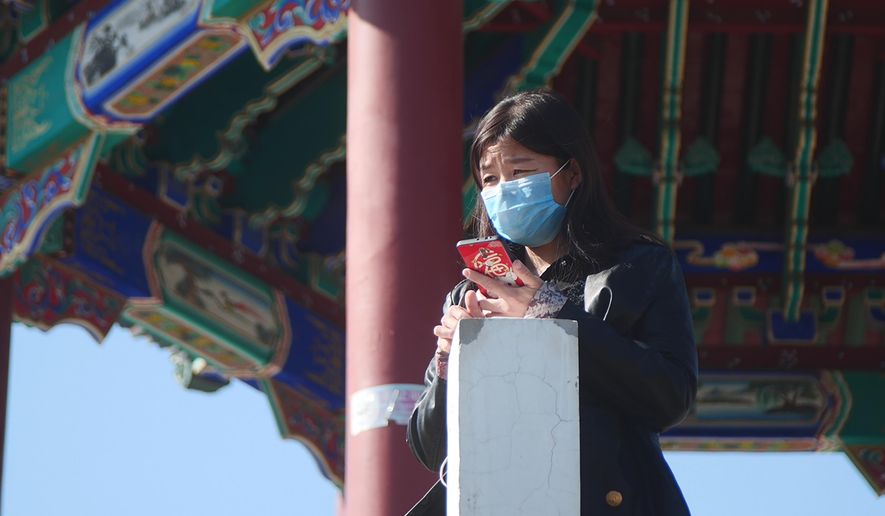 A woman wearing a face mask stands at a pagoda in Ritan Park in Beijing, Tuesday, Feb. 18, 2020. A hospital director who helped lead the fight against China's new virus has become one of its victims. His death comes as authorities are cautiously cheering a reduction in the number of new daily cases and deaths, along with the results of a study showing most people who contract the virus experience only mild symptoms. (AP Photo/Sam McNeil)