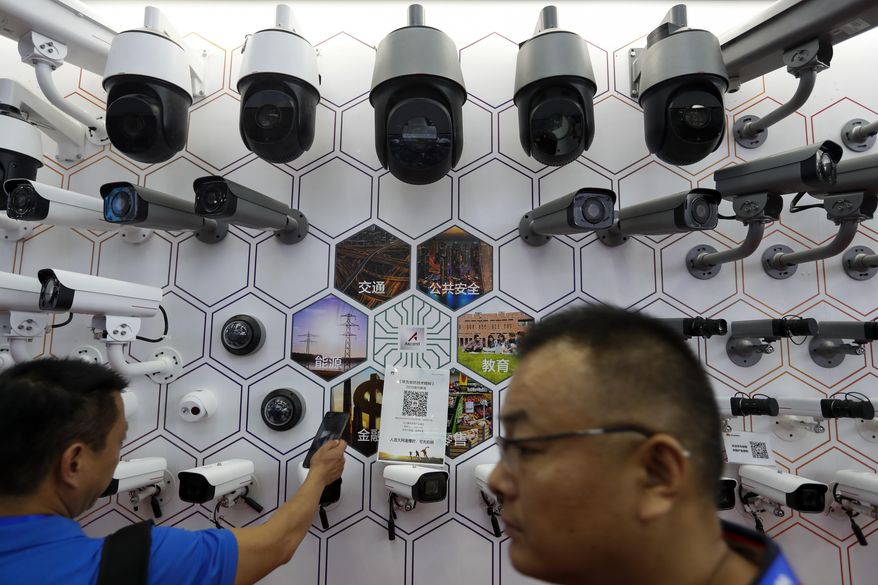 In this Oct. 29, 2019, file photo visitors look at the surveillance cameras by China&#x27;s telecoms equipment giant Huawei on display at the China Public Security Expo in Shenzhen, China&#x27;s Guangdong province. Sam Brownback, the former U.S. envoy for international religious freedom during the Trump administration, said Wednesday that China&#x27;s use of high-tech tools to repress its religious minorities will lead to more authoritarian crackdowns around the globe. (AP Photo/Andy Wong, File)