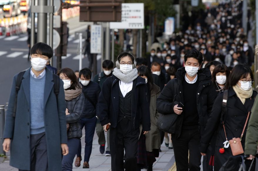People wear masks as they commute during the morning rush hour Thursday, Feb. 20, 2020, in Chuo district in Tokyo. A viral outbreak that began in China has infected more than 75,000 people globally. More than 1,000 cases have been confirmed outside mainland China. Most of the cases outside China involve people from a cruise ship quarantined at a Japanese port. (AP Photo/Kiichiro Sato)