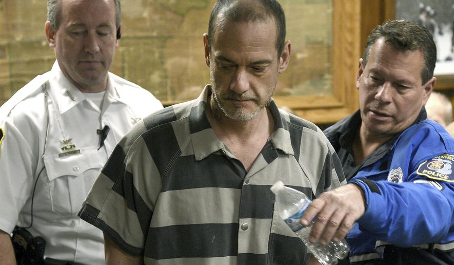 Sheriff Deputy Donald Duncan, left, and Monroe Police Cpl. Dino Mancini, righ, escort Kenny McBride into a courtroom Wednesday morning, Feb. 19, 2020, in Monroe, Mich. McBride, 45, is charged with multiple felonies, including mutilation, in the murder of a 79-year-old Temperance woman who officials say was beheaded. (Tom Hawley/The Monroe News via AP)