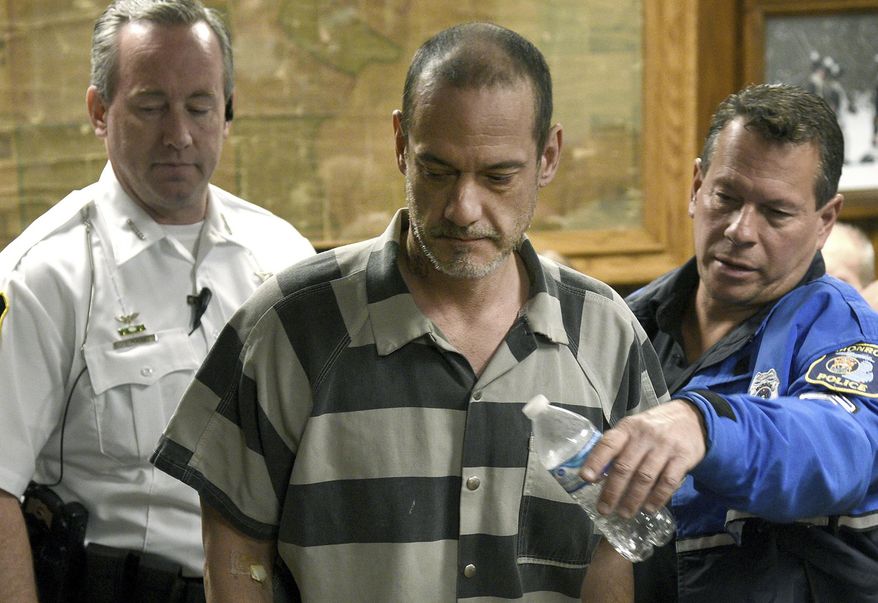 Sheriff Deputy Donald Duncan, left, and Monroe Police Cpl. Dino Mancini, righ, escort Kenny McBride into a courtroom Wednesday morning, Feb. 19, 2020, in Monroe, Mich. McBride, 45, is charged with multiple felonies, including mutilation, in the murder of a 79-year-old Temperance woman who officials say was beheaded. (Tom Hawley/The Monroe News via AP)