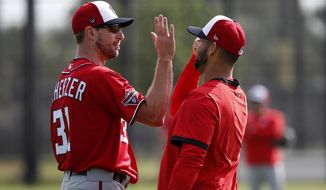Washington Nationals pitcher Max Scherzer, left, gets a high-five from fellow pitcher Anibal Sanchez during spring training baseball practice Friday, Feb. 14, 2020, in West Palm Beach, Fla. (AP Photo/Jeff Roberson)