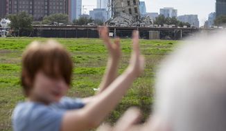 Randy Gibson takes a photo of his son Andrew, 11, in front of the &#39;Leaning Tower of Dallas&#39; on Monday, Feb. 17, 2020 in Dallas. A demolition of the former Affiliated Computer Services tower on Sunday morning left the central core behind. (Juan Figueroa/The Dallas Morning News via AP)