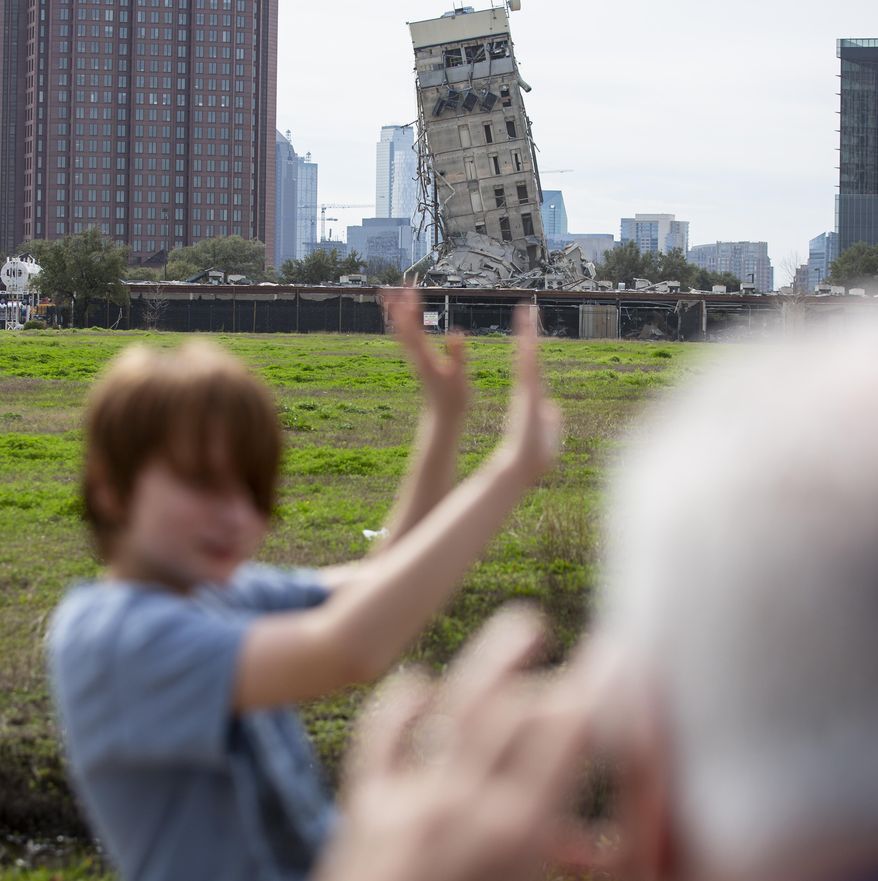 Randy Gibson takes a photo of his son Andrew, 11, in front of the &#x27;Leaning Tower of Dallas&#x27; on Monday, Feb. 17, 2020 in Dallas. A demolition of the former Affiliated Computer Services tower on Sunday morning left the central core behind. (Juan Figueroa/The Dallas Morning News via AP)