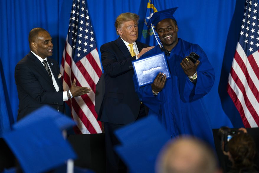 President Donald Trump hands out diplomas after delivering the commencement address at the "Hope for Prisoners" graduation ceremony, Thursday, Feb. 20, 2020, in Las Vegas. (AP Photo/Evan Vucci)