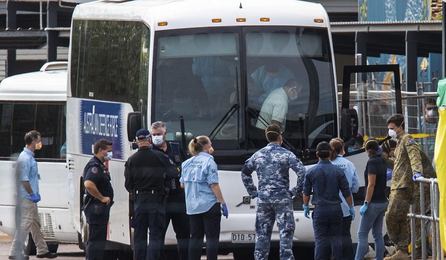 Government agencies gather beside buses to be used to take evacuees to a quarantine facility after arriving in Darwin, Australia, Thursday, Feb. 20, 2020. The evacuees have travelled from Japan after being stranded on the cruise ship Diamond Princess. (Helen Orr/AAP Image via AP)