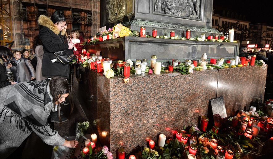 People place candles and flowers at a monument on the market place during a mourning for the victims of the shooting in Hanau, Germany, Thursday, Feb. 20, 2020. A 43-year-old German man shot and killed nine people at several locations in a Frankfurt suburb overnight in attacks that appear to have been motivated by far-right beliefs, officials said Thursday. (AP Photo/Martin Meissner)