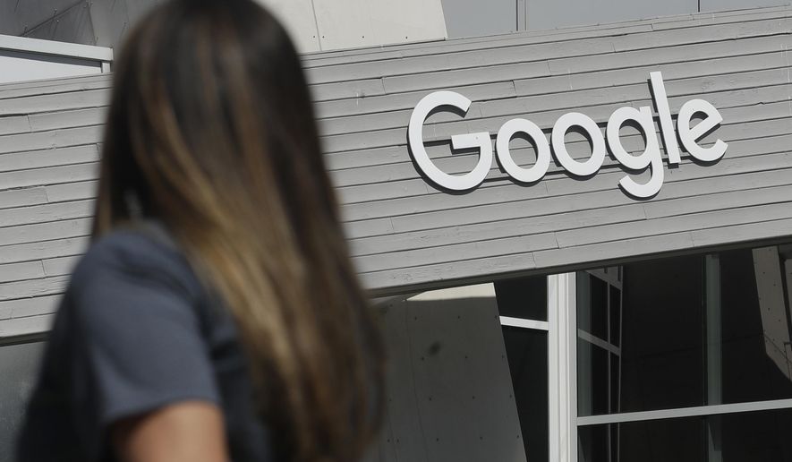 In this Sept. 24, 2019, file photo, a woman walks below a Google sign on the campus in Mountain View, Calif. (AP Photo/Jeff Chiu, File)