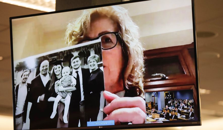 Gillian Millane, mother of murdered British backpacker Grace, holds up a photo during her victim impact statement via video link from England, at the sentencing of the man found guilty of her murder at the Auckland High Court in Auckland, New Zealand, Friday, Feb. 21, 2020. The killer, who has name suppression, has been sentenced to life imprisonment with a minimum non-parole period of 17 years. (Dean Purcel/New Zealand Herald via AP)