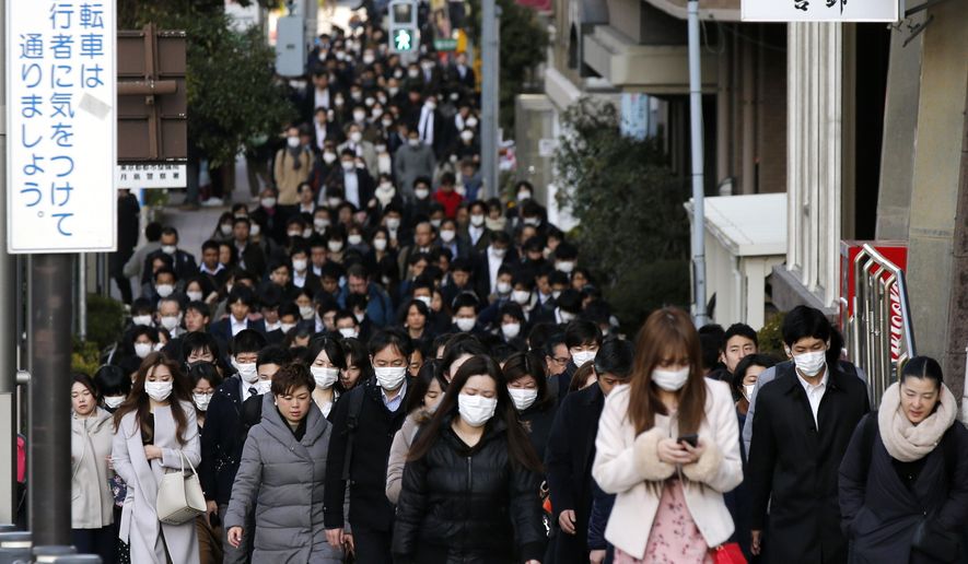 People wear masks as they commute during the morning rush hour Thursday, Feb. 20, 2020, in Chuo district in Tokyo. A test event for the Tokyo Olympics scheduled for later this month that would have involved some non-Japanese athletes is being rejiggered because of fear of the spreading virus from China. It will now involve only Japanese athletes. (AP Photo/Kiichiro Sato)