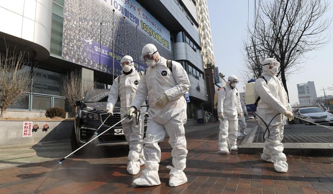 Workers wearing protective gears spray disinfectant against the new coronavirus in front of a church in Daegu, South Korea, Thursday, Feb. 20, 2020. The mayor of the South Korean city of Daegu urged its 2.5 million people on Thursday to refrain from going outside as cases of the new virus spike. (Kim Jun-beom/Yonhap via AP)