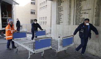 FILE - In this Friday, Feb. 21, 2020, file photo, personnel carry new beds inside a hospital of Codogno, near Lodi in Northern Italy. Health officials reported the country&#39;s first cases of contagion of COVID-19 in people who had not been in China. Italy saw cases of the new virus more than quadruple in a day as it grapples with infections in a northern region that apparently have spread through a hospital and a cafe. (AP Photo/Luca Bruno)