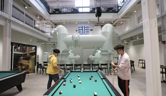 Jay Trinh, left, and Lamar Nguyen, both freshmen at Beloit College from Vietnam, play a game of pool in the college&#39;s new Powerhouse facility, a 120,000 square-foot student center that was formerly the Blackhawk Generating Station on the Rock River, in Beloit, Wis., Wednesday, Feb. 12, 2020. The pipes in the background were part of the water intake system for the power plant. (Amber Arnold)/Wisconsin State Journal via AP)