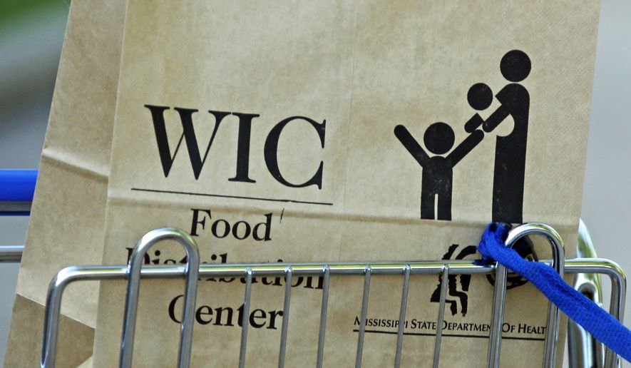 FILE - In this Oct. 3, 2013, file photo a Special Supplemental Nutrition Program for Women, Infants and Children, better known as WIC, bag sits in a shopping cart in Jackson, Miss. As the new public charge rule taking effect Monday, Feb. 24, 2020, has approached, droves of immigrants including citizens and legal residents have dropped government social services they or their children may be entitled to out of fear they will be kicked out of the U.S.  (AP Photo/Rogelio V. Solis, File)
