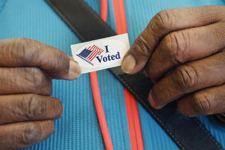 Loretta Haynes, of Cambridge, Mass., shows her sticker, Monday, Feb. 24, 2020, at the Cambridge City Hall annex, after she voted on the first morning of early voting in Massachusetts. (AP Photo/Elise Amendola)