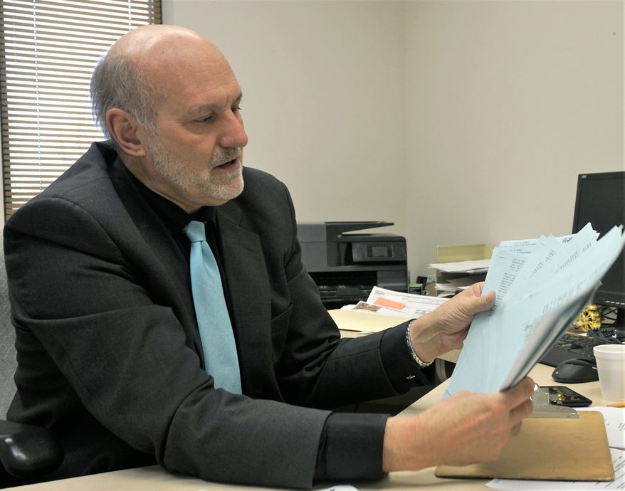 In this Feb. 10, 2020 photo, Minot City Assessor Kevin Ternes holds commercial assessment documents in his office in Minot City, N.D. Ternes plans to retire from the city Feb. 28 and open a commercial appraisal office. (Jill Schramm/Minot Daily News via AP)