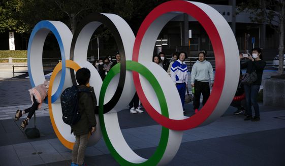 People wait in line to take pictures with the Olympic rings near the New National Stadium, Sunday, Feb. 23, 2020, in Tokyo. (AP Photo/Jae C. Hong)