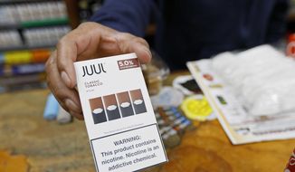 In this June 17, 2019, file photo, a cashier displays a packet of tobacco-flavored Juul pods at a store in San Francisco.  (AP Photo/Samantha Maldonado, File)