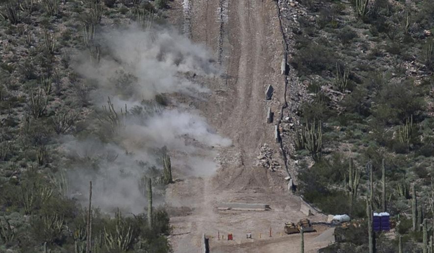 Construction crew perform a controlled detonation at the base of Monument Hill in Organ Pipe Cactus National Monument west of Lukeville, Ariz., on Wednesday, Feb. 26, 2020. Construction crews in southern Arizona have recently began blasting hills at the site to clear space for a new border wall system, bulldozing through a place called Monument Hill to construct a 30-foot (9-meter) steel wall along the U.S.-Mexico border. (Josh Galemore/Arizona Daily Star via AP)