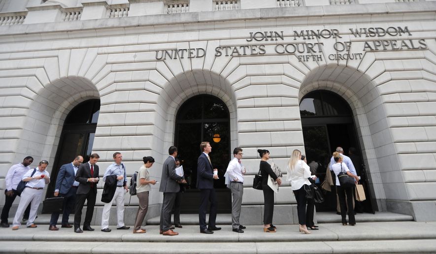 FILE - In this July 9, 2019 file photo, people wait in line to enter the 5th Circuit Court of Appeals in New Orleans. On Wednesday, Feb. 26, 2020, the federal appeals court said the winner-take-all system Texas uses to assign Electoral College presidential votes is constitutional. Wednesday's ruling is the latest defeat for organizations that say each state's electors should be chosen proportionally, based on the percentage of the statewide vote. (AP Photo/Gerald Herbert, File)