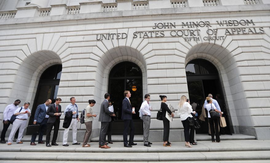 FILE - In this July 9, 2019 file photo, people wait in line to enter the 5th Circuit Court of Appeals in New Orleans. On Wednesday, Feb. 26, 2020, the federal appeals court said the winner-take-all system Texas uses to assign Electoral College presidential votes is constitutional. Wednesday's ruling is the latest defeat for organizations that say each state's electors should be chosen proportionally, based on the percentage of the statewide vote. (AP Photo/Gerald Herbert, File)